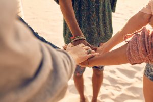friends at the beach putting hands together PXCW68T